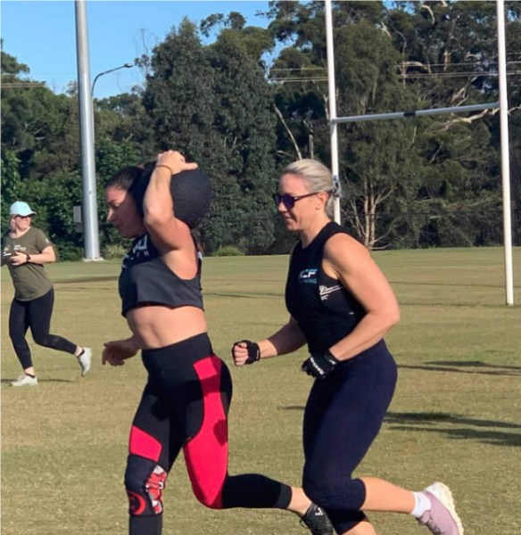 Naomi Lewin carrying a sandbag at a fitness event