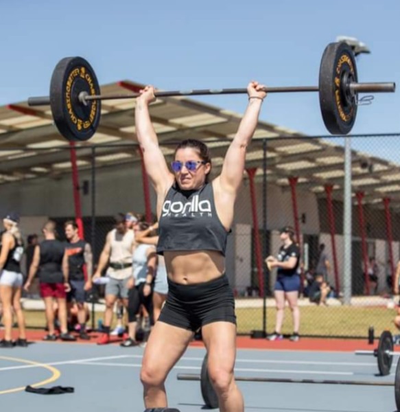 Naomi Lewin locking out a barbell overhead at a fitness event